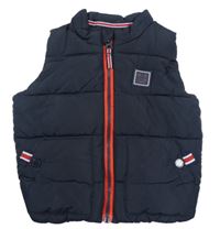 Tmavomodrá prešívaná šušťáková zateplená vesta s nášivkou Next