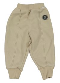 Béžové tepláky s pukmi a domečkem